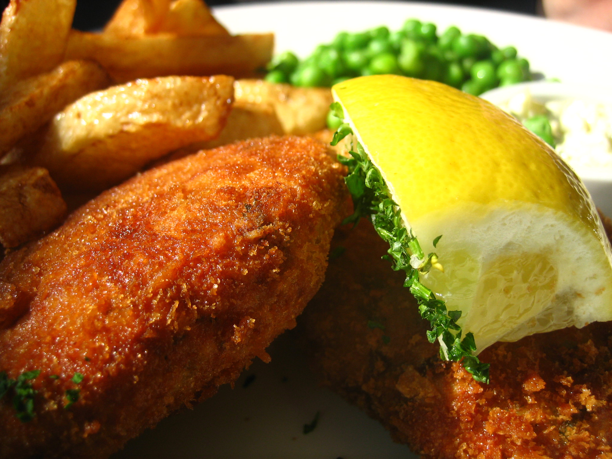 Goldenbrown fried fishcakes with fries and a lemon wedge