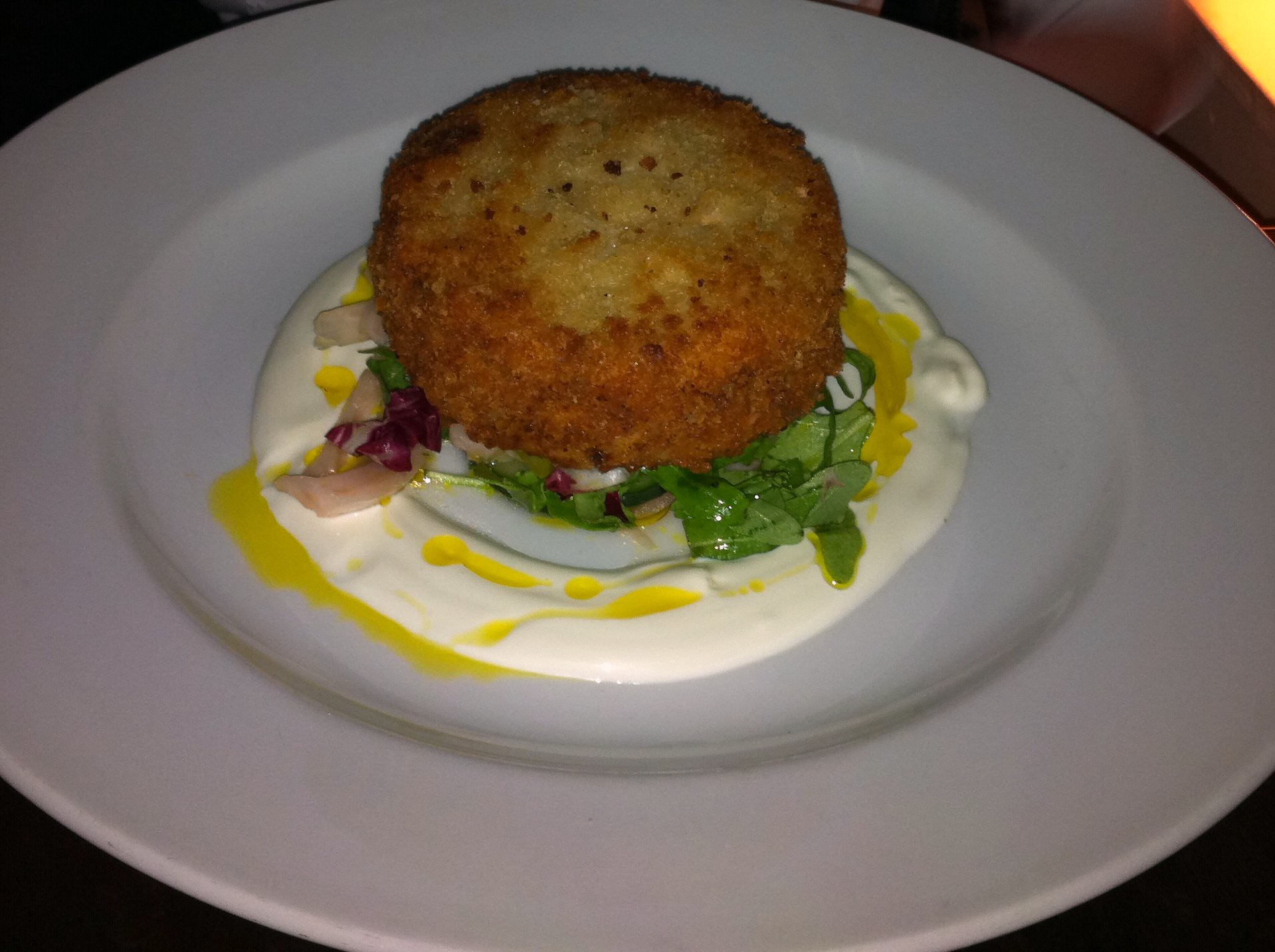 a plate with a fishcake on it served on some tartar sauce